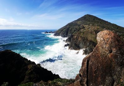 Scenic view of sea and mountains against blue sky