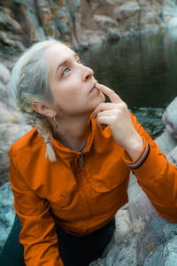 Close-up of woman looking up sitting by lake