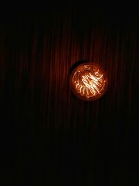 Close-up of illuminated light bulb against black background