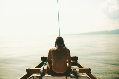 Rear view of man looking at sea against sky