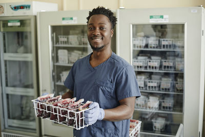 Smiling lab technician holding blood bags