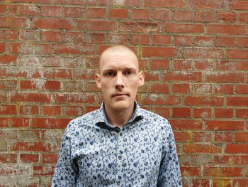 Portrait of man standing against brick wall