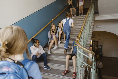 Male and female students having fun on steps at school