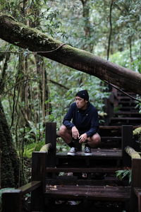 Young man sitting on wood in forest