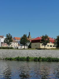 Houses by river and buildings against clear sky