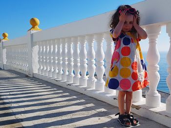 Woman standing by railing against sky