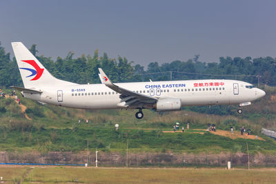 Side view of airplane on runway against sky