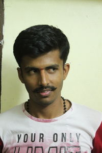 Portrait of young man standing against wall