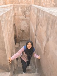 Full length portrait of woman standing against wall