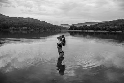 Woman standing in lake against sky