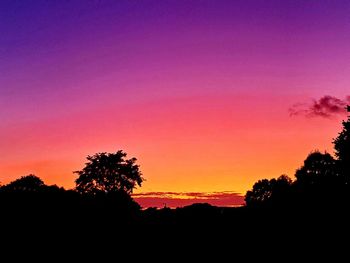 Silhouette trees against dramatic sky during sunset