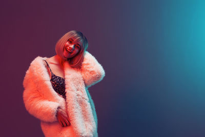 Portrait of woman standing against blue background