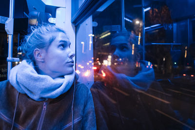 Young woman looking through window in vehicle at night