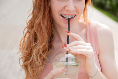 Midsection of woman drinking lemonade outdoors