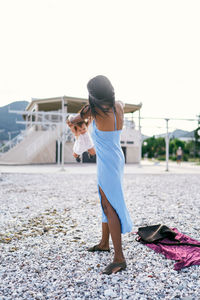 Woman with umbrella standing in city against clear sky