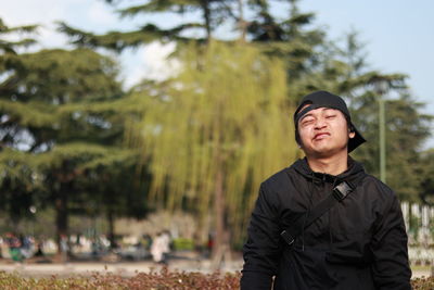 Portrait of young man standing against trees