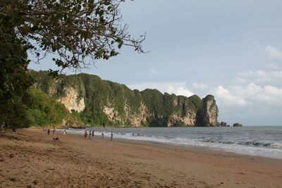 People on beach by mountain against sky