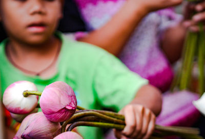 Midsection of girl holding pink flowers