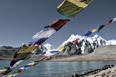 Prayer flags on strings at lakeside with snowcapped mountains in background