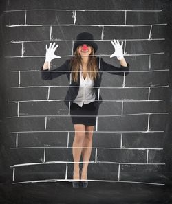 Full length portrait of woman standing against wall