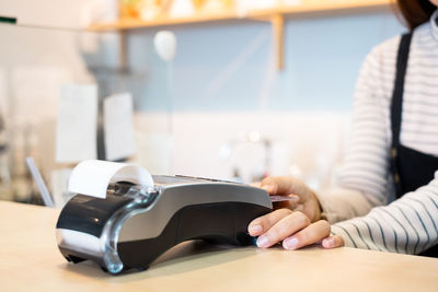 Midsection of woman using smart phone on table