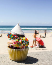 Close-up of cupcakes on beach against sky