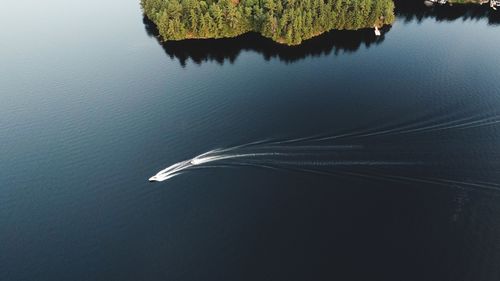 High angle drone view of speeding boat on calm lake