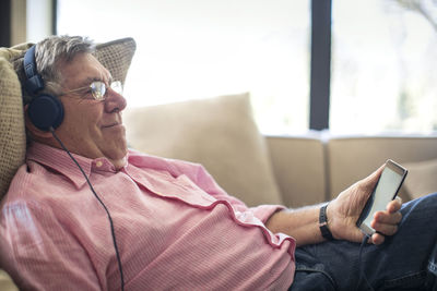 Relaxed senior man wearing headphones listening to music at home