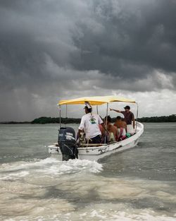 People on boat in sea against sky