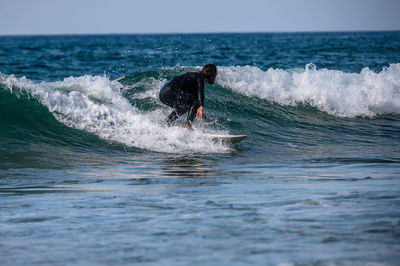 Man surfing in sea against sky