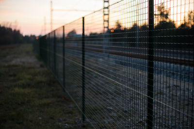 Close-up of fence against sky during sunset