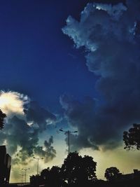 Low angle view of trees against cloudy sky