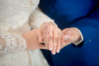 Midsection of bride and bridegroom holding hands during wedding ceremony