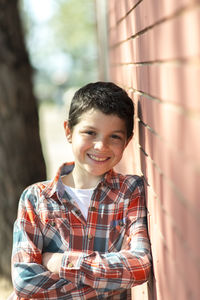 Portrait of smiling boy leaning on brick wall