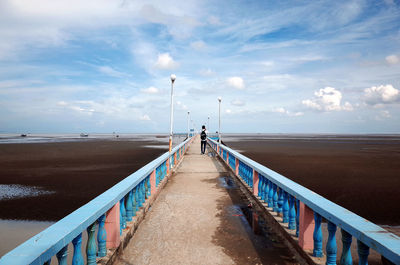 Rear view of people walking on pier