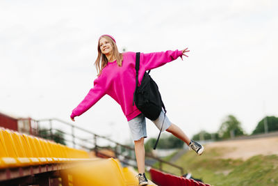 Full length of young woman exercising on field