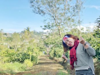 Smiling mid adult woman standing by plants against sky