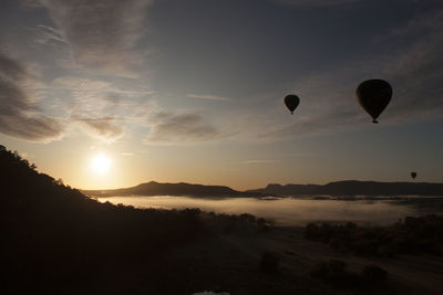 Hot air balloons flying against sky during sunset