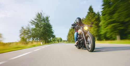 Man riding motorcycle on road against sky