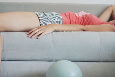 Midsection of woman lying on sofa at home