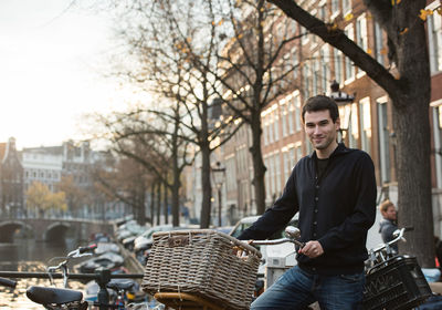 Portrait of young man with bicycle in city