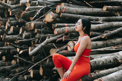 Low angle view of young woman sitting on log