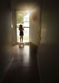 Rear view of girl standing by door at home