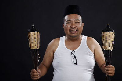 Portrait of man holding ice cream against black background