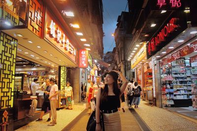 Woman standing on illuminated street in city at night