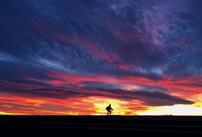 Silhouette man against orange sky