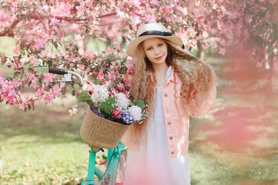 Portrait of beautiful young woman standing by pink flower