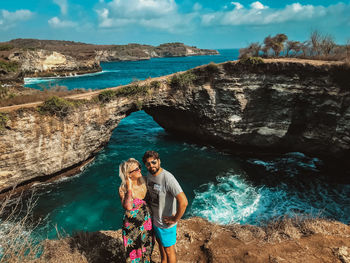 Young couple standing on rock by sea