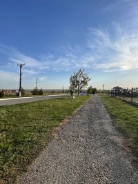 Road amidst field against sky