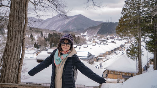 Portrait of smiling woman standing on snow covered mountains